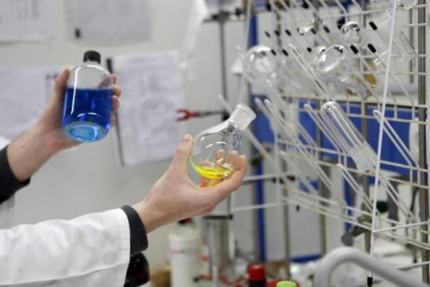 Un chimiste dans un laboratoire, qui manipule des fioles de prochuits chimiques