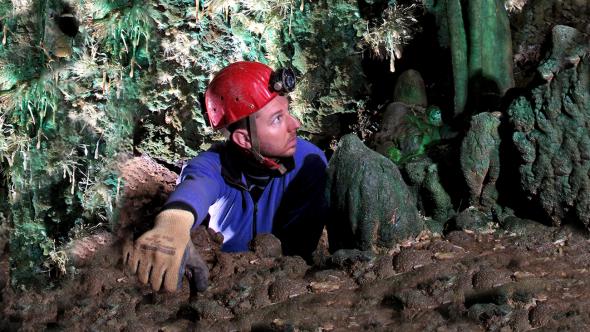 Image d'un spéléologue dans une grotte avec des stalagtites vertes