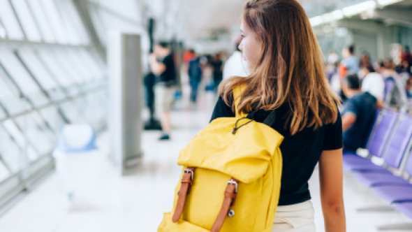 jeune femme avec sac-à-dos jaune dans un aéroport
