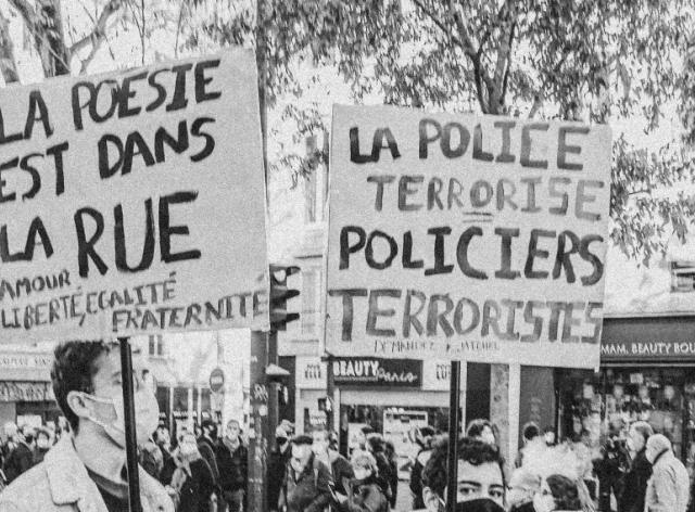 Des manifestants avec des panneaux affichant des messages "la poésie est dans la rue" et "la police terrorise, policiers terroristes"