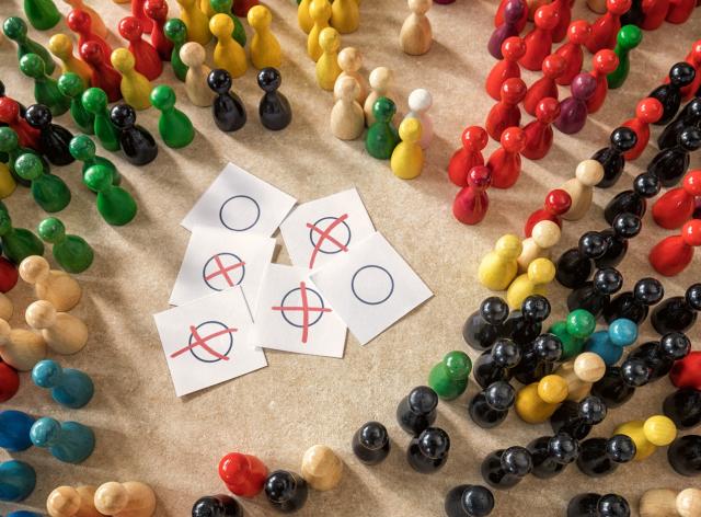 Représentation d'un vote symbolisé par des feuillets oui, non et des pions de multiples couleurs
