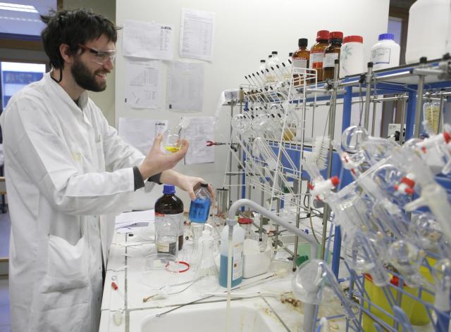 Un chimiste dans un laboratoire, qui manipule des fioles de produits chimiques