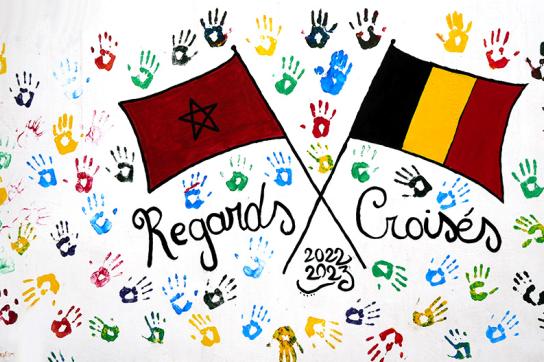 Deux drapeaux (Belgique et Maroc) croisés sur une toile blanche colorée de mains multicolores