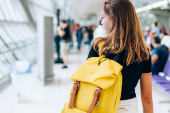 jeune femme avec sac-à-dos jaune dans un aéroport